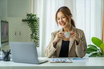 Young beautiful Asian businesswomen drinking coffee and using a computer laptop