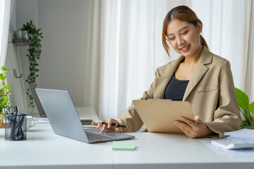 A beautiful Asian woman is working on collecting documents and information of the company's financial performance for the meeting. Account Analysis and Audit