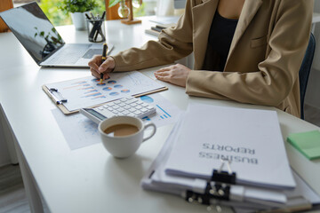 Fototapeta premium A beautiful Asian woman is working on collecting documents and information of the company's financial performance for the meeting. Account Analysis and Audit