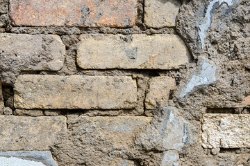Old bricks inside the wall of a destroyed building with peeled off plaster, close-up.