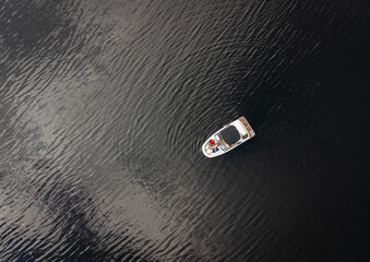Aerial view of power boat anchored on dark waters of a lake.