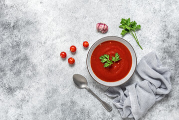 Tomato cream soup in a bowl, gray grunge background. View from above, flat lay. Organic vegan soup.