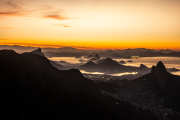 Beautiful view to layers of mountains and city during orange sunrise