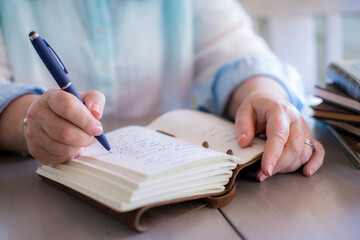 Close-up of white woman's hands writing in a journal