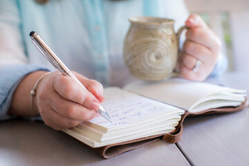 Close-up of white woman's hands writing in a journal