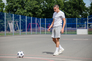 A Nineteen Year Old Teenage Boy Playing Football in A Public Park