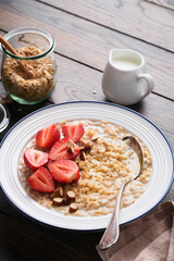 Oatmeal. Bowl of oatmeal porridge with strawberry, almond and milk on old wooden dark table background. Top view in flat lay style. Natural ingredients. Hot and healthy breakfast and diet food.
