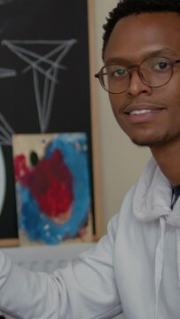 Vertical video: Portrait of smiling man drawing vase sketch on white canvas, sitting in art class workshop. Student learning to draw masterpiece with srtistic tools for personal growth and development
