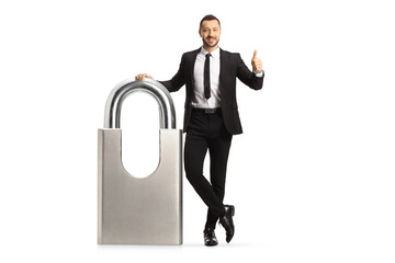 Businessman leaning on a big padlock and gesturing thumbs up