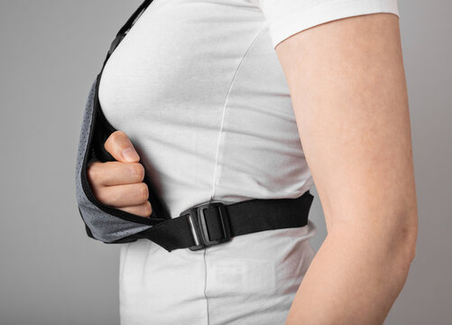 Woman wearing sling to support injured arm. Elbow, shoulder, forearm, wrist pain caused by trauma, injury, chronical disease. Healing process. High quality photo