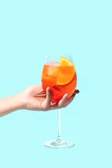 Poster Aperol Spritz cocktail on a girls hand on blue background © Valeriia Horovets