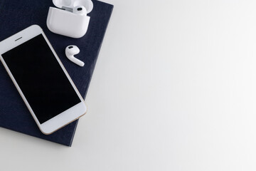 modern white table with notebook phone wireless headphones top view with space for text. Flat lay Business workplace and objects
