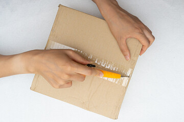 Unboxing the courier box with a cutter knife