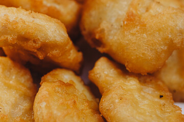 Close up of chicken nuggets in basket with parchment paper and chili tomato sauce on wooden background.