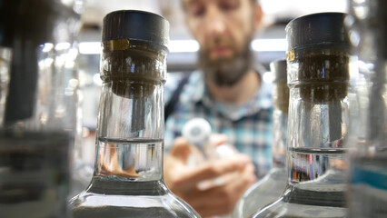 Close-up of glass bottles with gin or vodka and a male buyer takes one