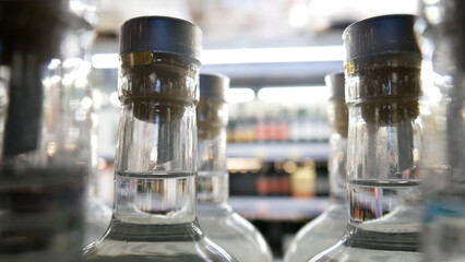 Close-up of glass bottles with gin or vodka on the shelf of an alcohol store