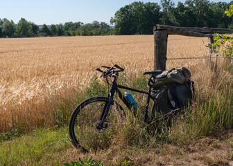 Fototapeta na wymiar Bicycle in the field outdoors. Break on the road. Long journey. Adventure on wheels. Healthy, active lifestyle. The world. Wheat field. Summer vacation. bike tour