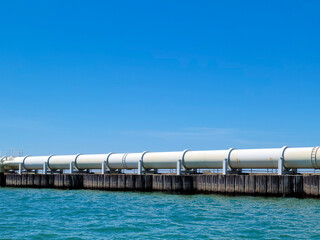 White industrial pipeline on Lake Michigan with bright blue sky 