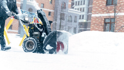 a janitor on a snowplow removes snow in the courtyard of a residential building