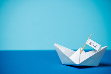 sos paper boat on blue background