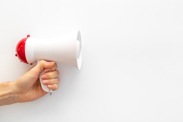 Hand holding megaphone against the empty wall. Hiring or advertising concept