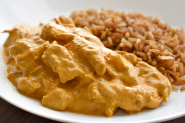 Indian chicken curry with fried rice on a white plate.