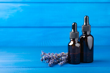 Lavender essential oil on blue texture wood background. Spa concept. RELAX. Aroma oil with lavender aroma. Copy space. Place for text. - obrazy, fototapety, plakaty