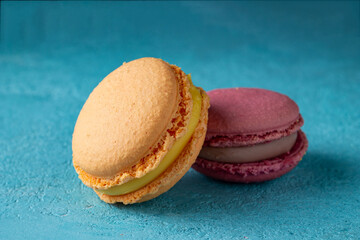 two colored macaroons lie on a blue background, selective focus