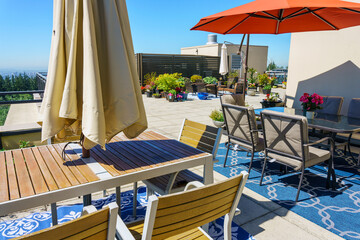 Patio furniture grouping on huge rooftop patio garden with multiple tables, chairs and umbrellas.