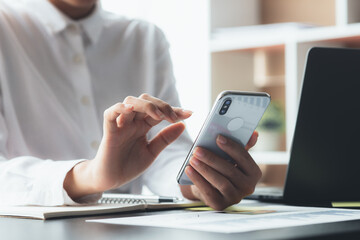young businesswoman looking at financial information from a mobile phone, she is checking company financial documents, she is a female executive of a startup company. Concept of financial management.