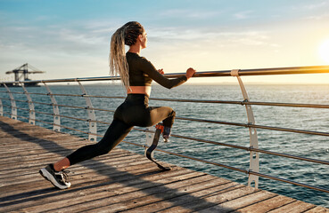 Fototapeta na wymiar Motivation and sports. Sports training of a woman with a prosthesis on a bridge with a view of the sea and sunrise.