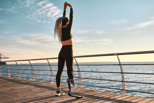 Morning warm-up at sunrise. Sports woman with a prosthetic leg is training. - Powered by Adobe