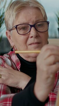 Vertical video: Portrait of elder woman drawing masterpiece on canvas, learning artistic skills in art class workshop. Educational program to develop personal growth and draw professional sketch model