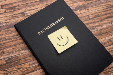 Adhesive note with a smiley on a Bachelorarbeit (bachelor thesis). Printed and bound thesis with a...