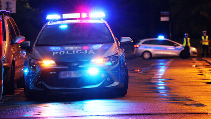 Incydent policji wieczorem w mieście.  - Sygnalizator błyskowy niebieski na dachu radiowozu policji polskiej w nocy. - obrazy, fototapety, plakaty