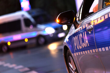 Incydent policji wieczorem w mieście.  - Sygnalizator błyskowy niebieski na dachu radiowozu policji polskiej w nocy.
