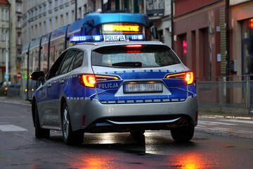 Incydent policji wieczorem w mieście.  - Sygnalizator błyskowy niebieski na dachu radiowozu policji polskiej w nocy. © FotoDax