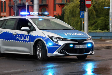 Incydent policji wieczorem w mieście.  - Sygnalizator błyskowy niebieski na dachu radiowozu policji polskiej w nocy.