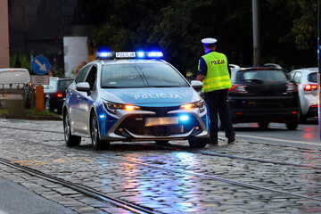 Incydent policji wieczorem w mieście.  - Sygnalizator błyskowy niebieski na dachu radiowozu policji polskiej w nocy. © FotoDax