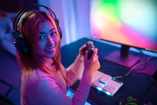 A Professional female pro gamer play online mobile games cyber sport and esport winner emotion. Young woman in tournament match worldwide in room colorful neon lights.