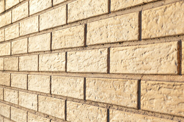 Perspective view of a yellow modern stone wall. There is a decorative texture on the surface of the bricks. Background.