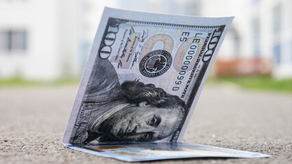 Close-up of a beautiful hundred dollar bill on the ground outdoors