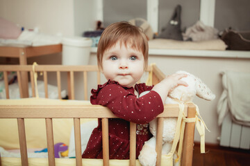 baby girl stands in a crib in a children's room