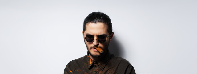 Studio portrait of young man with a cigar on white background. Panoramic banner.