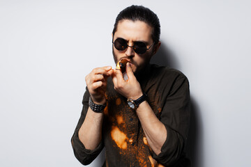 Close-up studio portrait of young man with a cigar on white background.