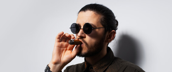 Studio portrait of young man with a cigar on white background. Panoramic banner.
