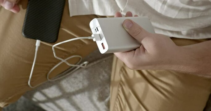The man plugs the cable into the power bank.