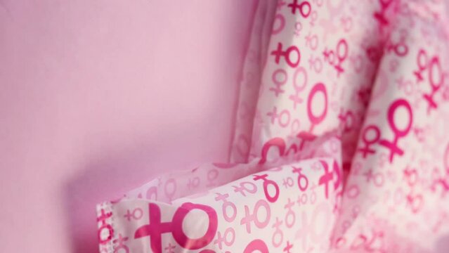 Vertical video of a hand taking a sanitary napkin with women symbol on pink background