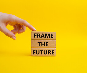 Frame the future symbol. Wooden blocks with words Frame the future. Beautiful yellow background. Businessman hand. Business and Frame the future concept. Copy space.