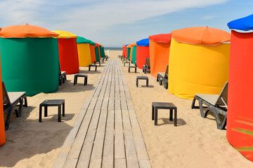 The typical colored tents and beach chairs - obrazy, fototapety, plakaty